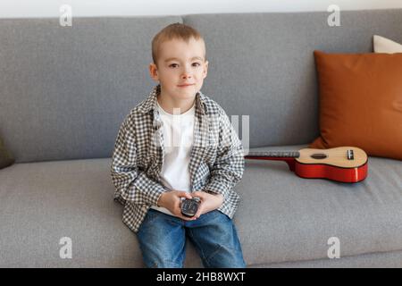 Telecomando TV per bambini. Ragazzo senza controllo genitori guardando la televisione. Istruzione della prima infanzia e tempo libero in età elementare. Foto Stock