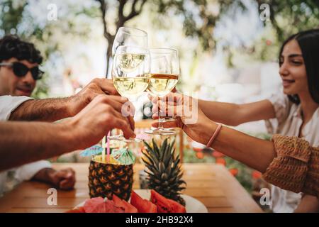 Amici felici che tostano vino bianco all'aperto - gruppo di giovani che si divertono a scottare i viticci Foto Stock