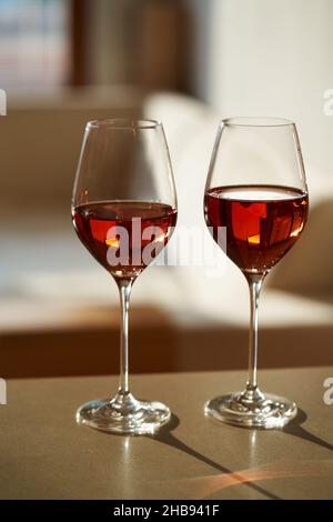 Due bicchieri di vino ancora rosato su un tavolo in un appartamento alla luce del sole Foto Stock