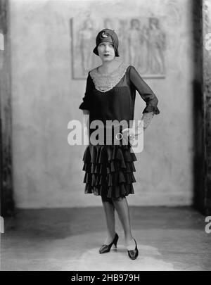 Giovane donna in abito 'flapper' e cappello di cloche in posa per il ritratto con le mani sui fianchi. Circa 1922 Foto Stock