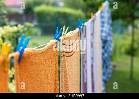 La lavanderia lavata è appesa sugli outddors del clothesline. Focalizzazione selettiva sul pin dei vestiti. Asciugando un asciugamano e un abbigliamento in cotone pulito e umido dopo il lavaggio Foto Stock
