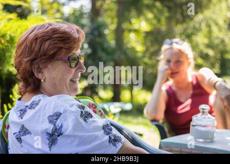 Due donne che si divertono a fare una pausa caffè all'aperto. Madre anziana sorridente durante la chat con sua figlia Foto Stock