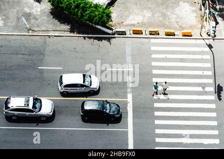 Salvador, Bahia, Brasile - 12 marzo 2017: Tre auto si sono arrestate e due persone che attraversano il crosswalk. Foto Stock