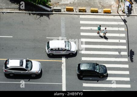 Salvador, Bahia, Brasile - 12 marzo 2017: Tre auto si sono arrestate e due persone che attraversano il crosswalk. Foto Stock