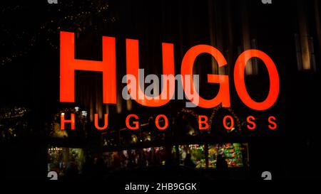 Scopri il logo di un negozio di designer Hugo Boss con il riflesso del mercato di Natale stand nel centro di Düsseldorf / Germania. Foto Stock