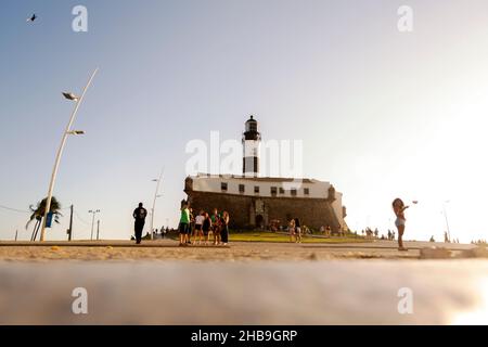 Vista dal basso di Farol da barra in Salvador, con piccioni che mangiano mais a terra e turisti che passeggiando. Foto Stock