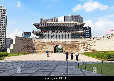 Porta Namdaemun o porta Sungnyemun all'ora blu con percorsi leggeri dai veicoli. Questo edificio storico e' circondato da alti edifici moderni. Foto Stock