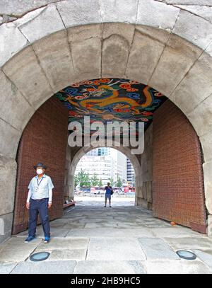 Porta Namdaemun o porta Sungnyemun all'ora blu con percorsi leggeri dai veicoli. Questo edificio storico e' circondato da alti edifici moderni. Foto Stock