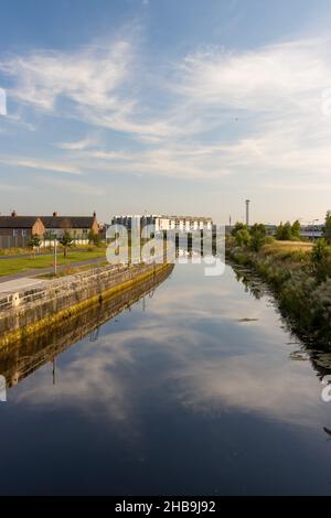 DUBLINO, IRLANDA - 25 luglio 2021: Un colpo verticale di un fiume con riflesso del cielo nel distretto docklands di Dublino Foto Stock