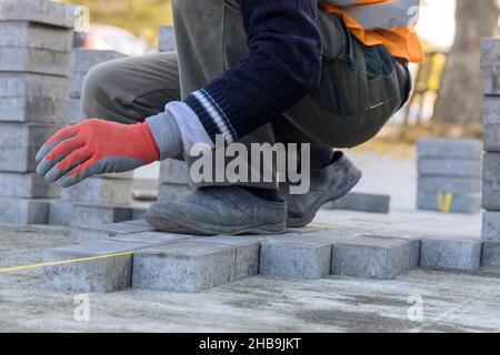 Installazione di mattoni di calcestruzzo durante la costruzione del marciapiede Foto Stock