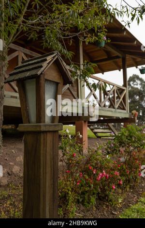 casa in legno con balcone accanto ad un bel giardino e una lampada, stile rustico della facciata con la natura, stile di vita Foto Stock