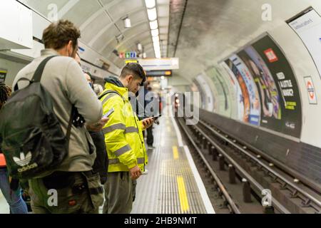 Pendolari serali in attesa sulla piattaforma della metropolitana per Londra Underground England UK Foto Stock