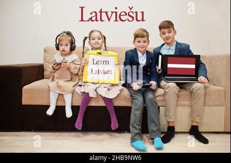 Quattro bambini mostrano iscrizione imparare lettone. Concetto di apprendimento delle lingue straniere. Latviesu. Foto Stock