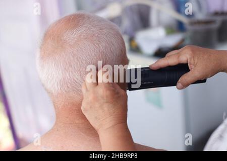 Donna anziana che ottiene un taglio di capelli a casa Foto Stock