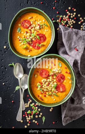 Deliziosa zuppa di lenticchie con pomodori ciliegini e panna. Zuppa di lenticchie gialla fatta di verdure. Foto Stock