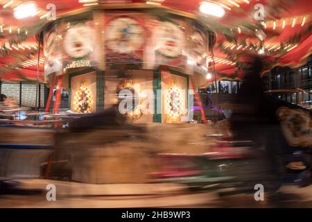 Notte colorata e illuminante atmosfera di persone, bambini e famiglie godere e giocare intorno giostra nel mercato di Natale a Düsseldorf, Germania. Foto Stock