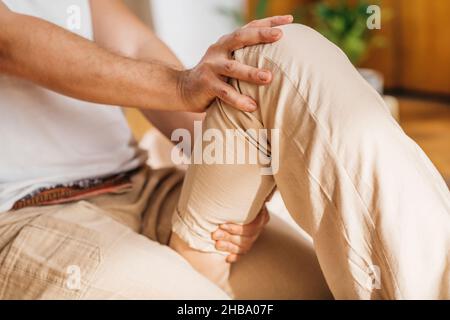 Massaggio tradizionale tailandese alle gambe. Massaggiatore Tailandese che esegue una rilassante tecnica di allungamento passivo su una gamba. Foto Stock