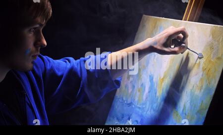 Artista copista paint seascape con nave in oceano. Fumo Vaper vape e-sigaretta. Artigiano arredatore disegnare come barca vela sul mare blu con colori acrilici. Foto Stock