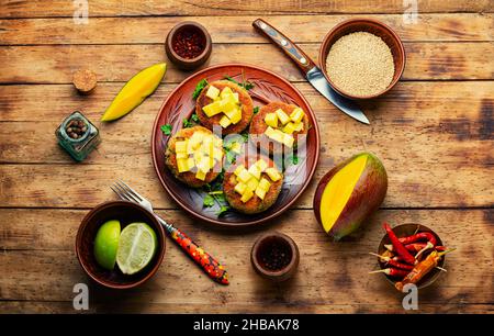 Cibo vegano, cotoletta di quinoa guarnita con mango. Hamburger vegetariano al forno Foto Stock