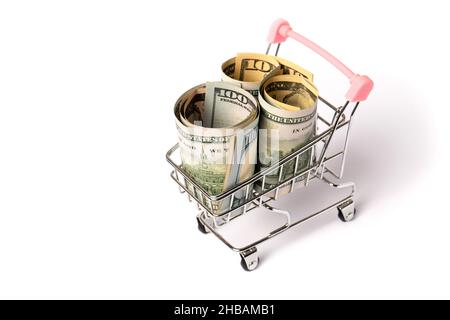 Il carrello della spesa con manico rosa riempito con cento rotoli di bolletta dollari isolato su sfondo bianco. Vista dall'alto Foto Stock