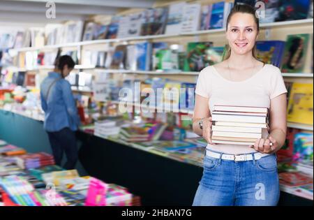 Donna ridente che acquista libri in copertina rigida Foto Stock