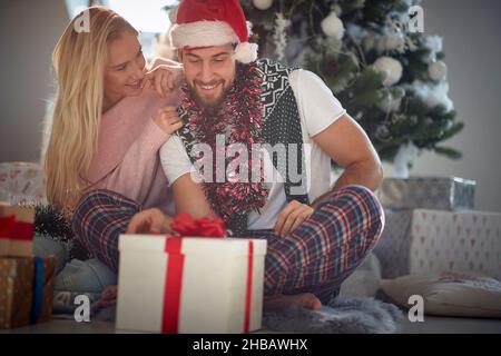 Gioiosa coppia caucasica scambio di regali di Natale in una mattinata di Natale Foto Stock