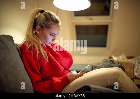 Giovane donna online con smartphone a Natale Foto Stock