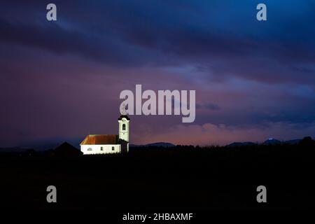 Vista della chiesa di san Simone e Giuda (Sveta Simona in Jude) al crepuscolo come le nuvole si susseguono, Spodnji Brnik, Slovenia. È anche possibile vedere la li Foto Stock