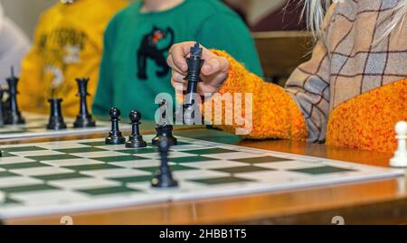 Bambino mano che muove il pezzo di scacchi a bordo, primo piano Foto Stock