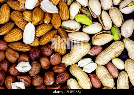 Vista dall'alto di diverse noci: Mandorle, pistacchi, arachidi, nocciole su sfondo metallico nero. Foto Stock