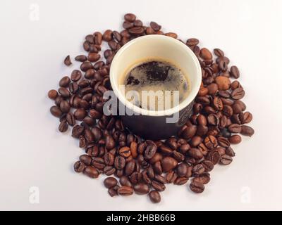 Tazza di caffè e chicchi di caffè. Chicchi di caffè su sfondo bianco con messa a fuoco morbida e luce sullo sfondo. Foto Stock