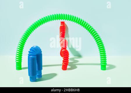Il tubo pop curvo è appoggiato contro la parete. Vita morta moderna con giocattolo antistress. Foto Stock