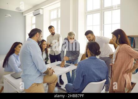Team di persone che hanno una conversazione con un uomo d'affari senior durante la riunione in ufficio Foto Stock
