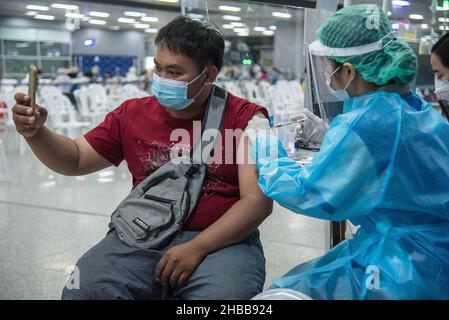 Bangkok, Tailandia. 18th Dic 2021. Un uomo prende un selfie mentre viene somministrato con una dose di vaccino Pfizer-BioNTech Covid-19 alla Bang sue Grand Station, Bangkok.Thailand ha accelerato i colpi di vaccinazione di Covid-19 e il colpo di richiamo in preparazione per una diffusione locale della variante di Omicron dopo che il Ministero della Salute della Thailandia ha detto la settimana scorsa che almeno 9 casi di Omicron erano stati scoperti in Thailandia. Credit: SOPA Images Limited/Alamy Live News Foto Stock