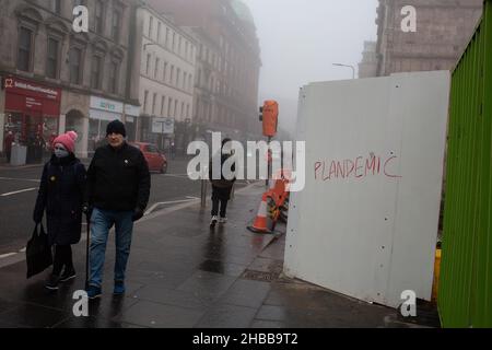 Glasgow, Regno Unito, 18th dicembre 2021. Gli amanti dello shopping natalizio passavano davanti ai graffiti Reading ÔPlandemicÕ, insinuando che il Coronavirus Covid-19 pandemic in pianificato dai governi, su Argyle Street, a Glasgow, Scozia, 18 dicembre 2021. Foto: Jeremy Sutton-Hibbert/ Alamy Live News. Foto Stock