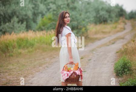 Giovane donna bionda con capelli lunghi in stile retrò vintage abiti con cestino pic-nic a piedi sul pianerottolo Foto Stock