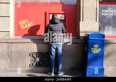 Barcellona, Spagna - Dicembre 10 2021: Uomo che usa ATM per estrarre denaro Foto Stock