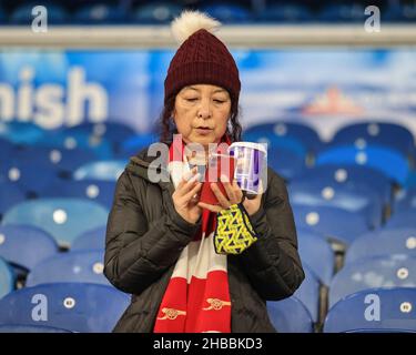 Un ventilatore dell'Arsenal controlla il suo telefono, tenendo un cioccolato caldo in questo pomeriggio freddo del sabato Foto Stock