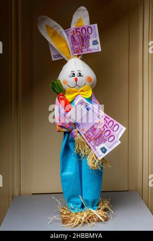 Coniglio felice imbottito che detiene due banconote da 500 euro con una banconota da 500 euro tra le orecchie, Foto Stock