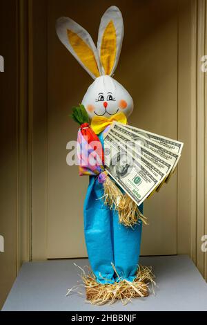 Coniglio felice imbottito che tiene un ventilatore di cento banconote di dollari statunitensi, Foto Stock