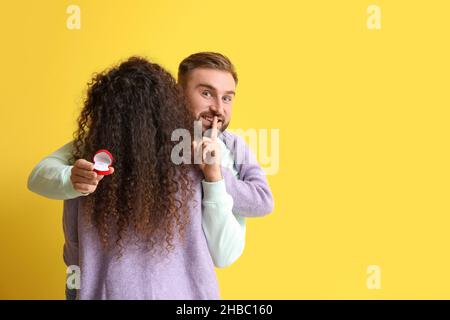 Il giovane che va a fare proposta alla sua ragazza su sfondo a colori Foto Stock