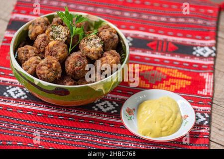 palle di carne fritte in un recipiente di argilla su un panno tradizionale Foto Stock