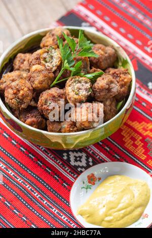 palle di carne fritte in un recipiente di argilla su un panno tradizionale Foto Stock