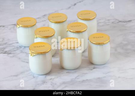 yogurt industriale al latte intero naturale in pentole di vetro con data di scadenza Foto Stock