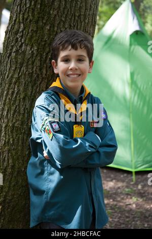 Un ritratto di ragazzo scout campeggio in Inghilterra con una tenda verde dietro di lui Foto Stock