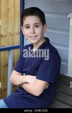 Ritratto di un ragazzo di dodici anni con le braccia piegate illuminate da luce ambientale Foto Stock