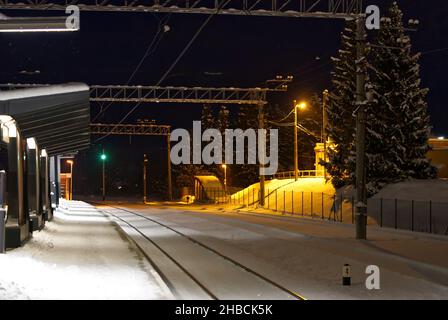 Piattaforma ferroviaria coperta di neve di notte. Estonia Lockal stazione ferroviaria. Foto Stock