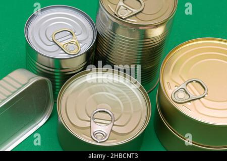 Un gruppo di lattine impilate con bordi vuoti su sfondo verde. Cibo in scatola. Diverse lattine di alluminio per la conservazione sicura e a lungo termine di alimenti. Contenitori per la conservazione di alimenti sigillati in acciaio Foto Stock