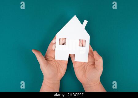 Tenendo una piccola casa di carta nelle mani, planando una nuova casa, bene immobile, proprietà Foto Stock