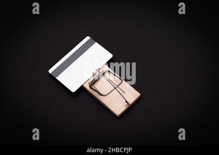 Rischio di credito e trappola di prestito - modello bianco carta di credito in legno mouse trappola su sfondo nero Foto Stock